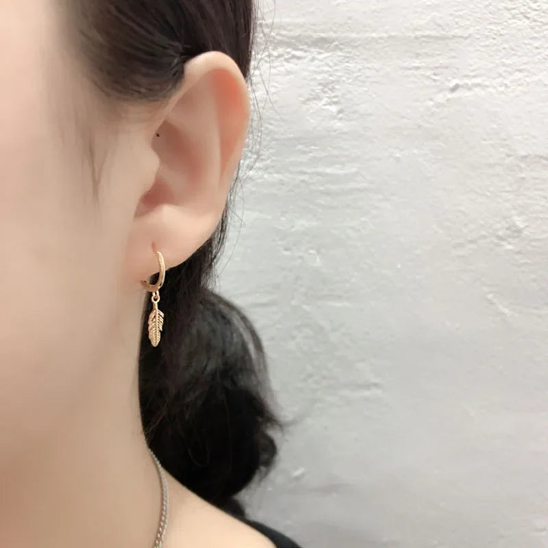 Gold hoop earrings with small dangling feather